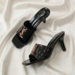 Ruby Mule Heel – Black glossy mule heel with gold-tone detailing and square-toe design.
