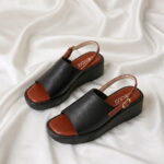 Aura Wedge Sandal – Black with open-toe design, slingback strap, and wedge sole.